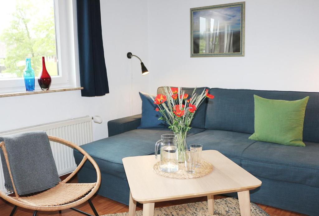 ブラウンラーゲにあるFerienapartment Bergstationのリビングルーム(青いソファ、花のテーブル付)