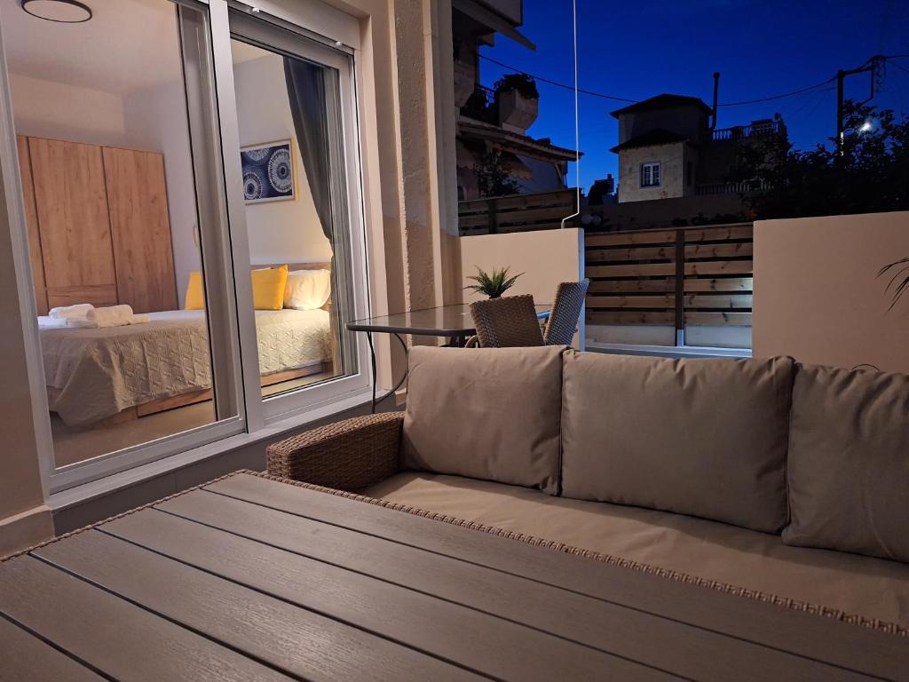 ein Sofa auf einem Balkon mit Blick auf ein Schlafzimmer in der Unterkunft modern apt near Heraklion city & airport in Néa Alikarnassós
