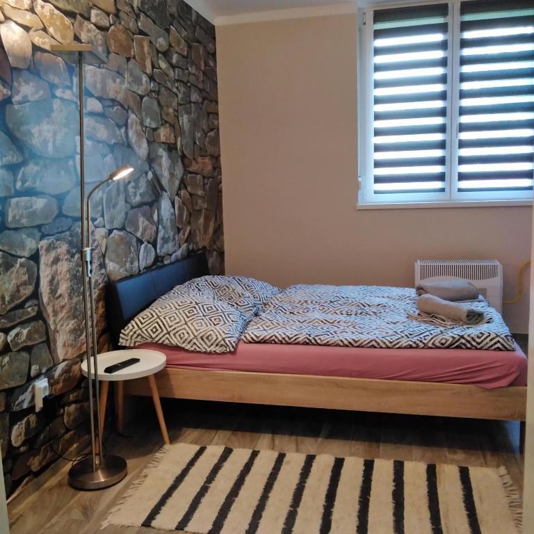a bedroom with a bed and a stone wall at Dési apartman in Kaposvár