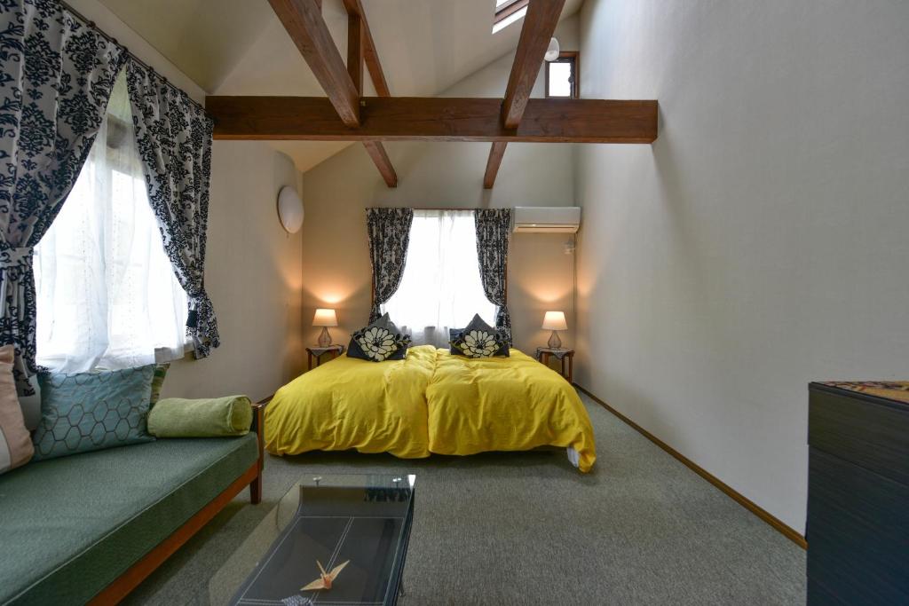 a bedroom with a yellow bed and a couch at Backcountry Lodge Hakuba in Hakuba