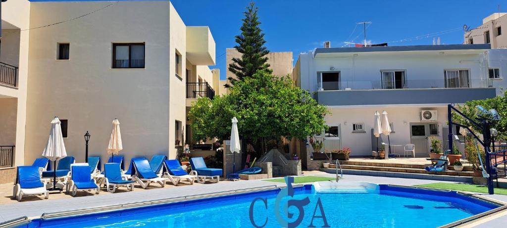 a pool with chairs and umbrellas next to a building at C & A Hotel Apartments in Polis Chrysochous