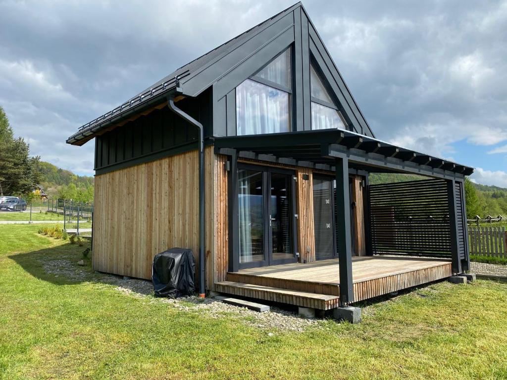 a small house with a wooden deck in a field at Love Wysove in Wysowa-Zdrój