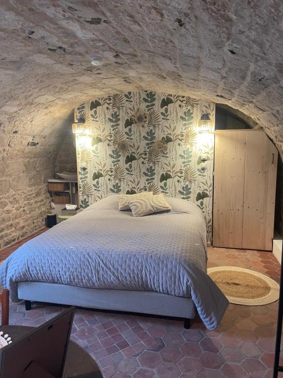 een slaapkamer met een bed in een stenen muur bij Sous la Glycine in Giverny