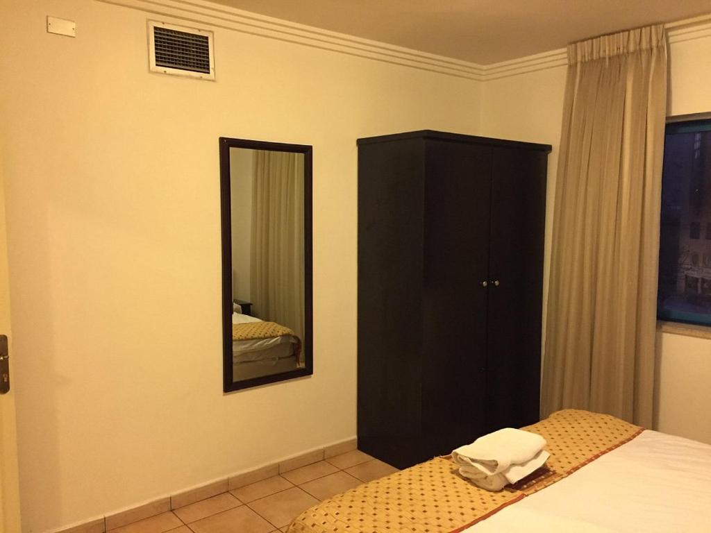 a bedroom with a black cabinet and a mirror at Jameel Guest House in At-Tafilah