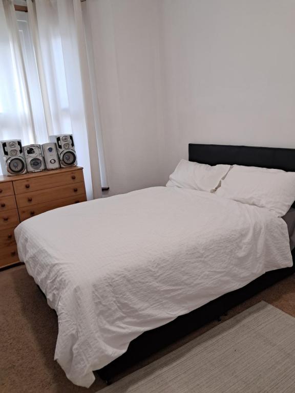a bedroom with a white bed with speakers on a dresser at New 2BED Kay Road SW9 London in London
