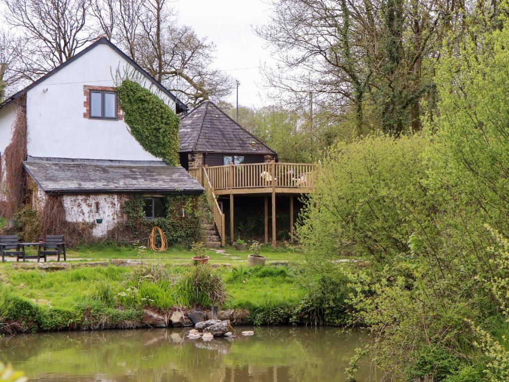 a house with a deck next to a body of water at The Roundhouse in Okehampton