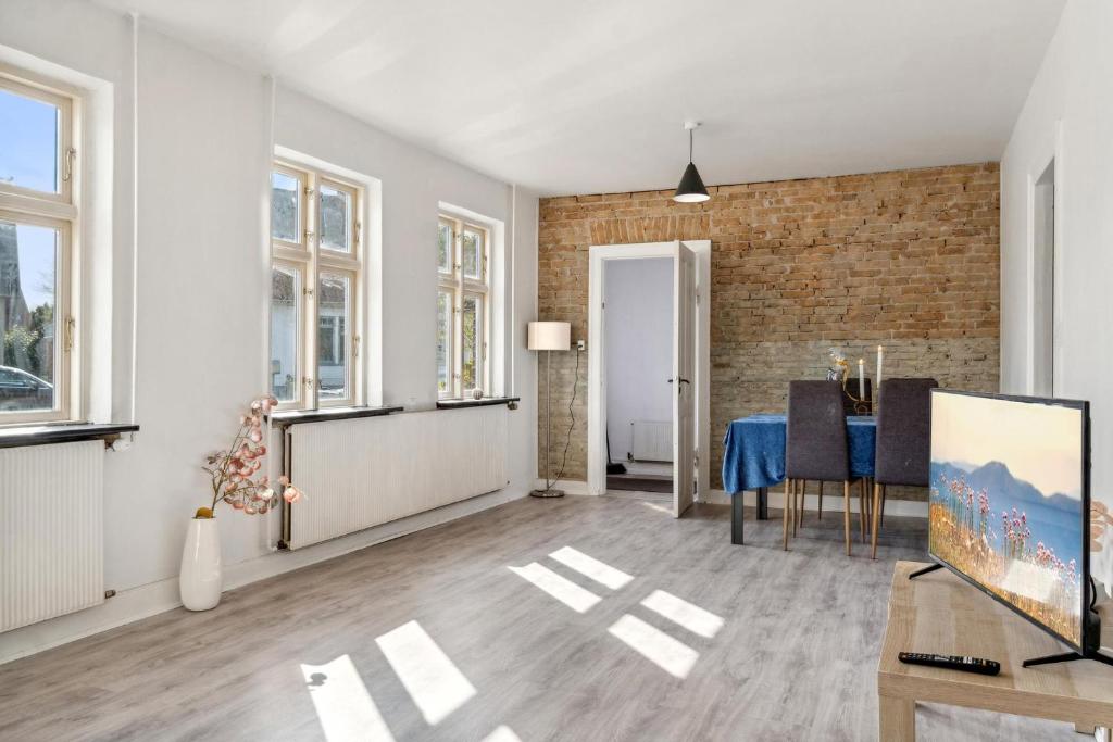 - un salon avec une table et un mur en briques dans l'établissement Town House in Fuglebjerg, à Fuglebjerg