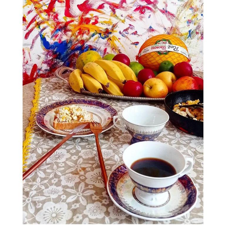 a table with a cup of coffee and a plate of fruit at Multitudenow in Florianópolis