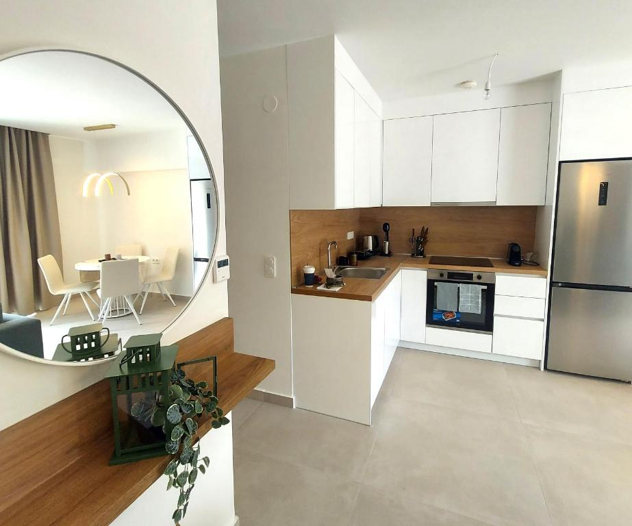 - une cuisine avec des placards blancs et un grand miroir dans l'établissement Athasi Resindences, à Thasos