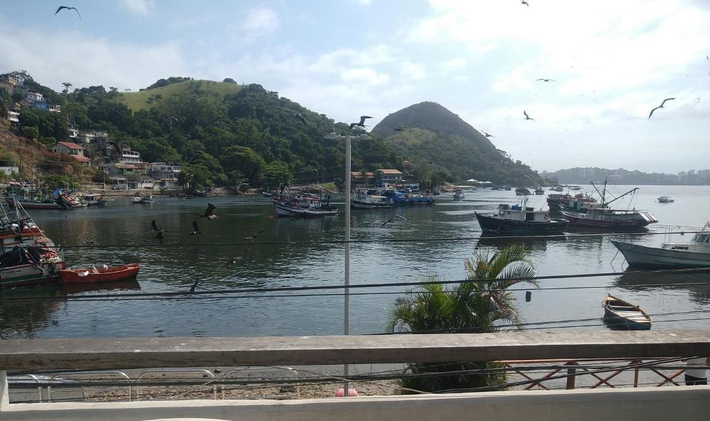 Un grupo de barcos en un río con montañas. en Pracinha do cais, en Niterói