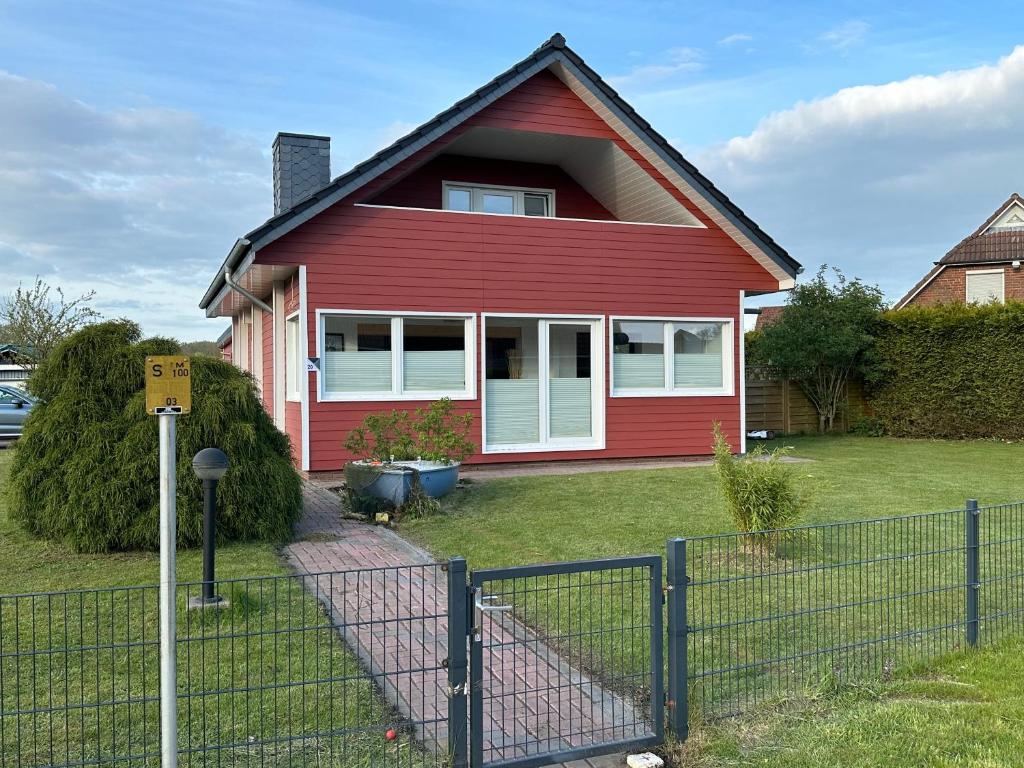 una casa roja con una valla delante en Ferienhaus Wiesenstrasse, en Neuhaus an der Oste