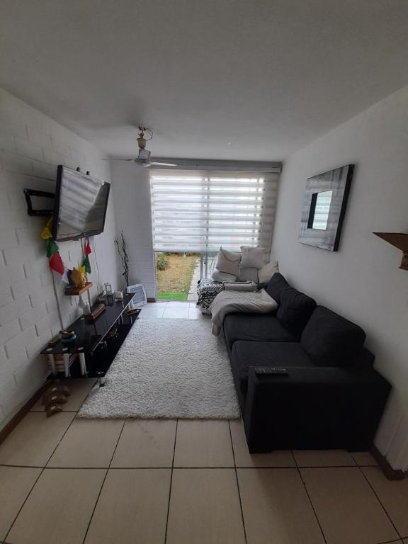 ein Wohnzimmer mit einem schwarzen Sofa und einem TV in der Unterkunft Nova Vida in Santiago