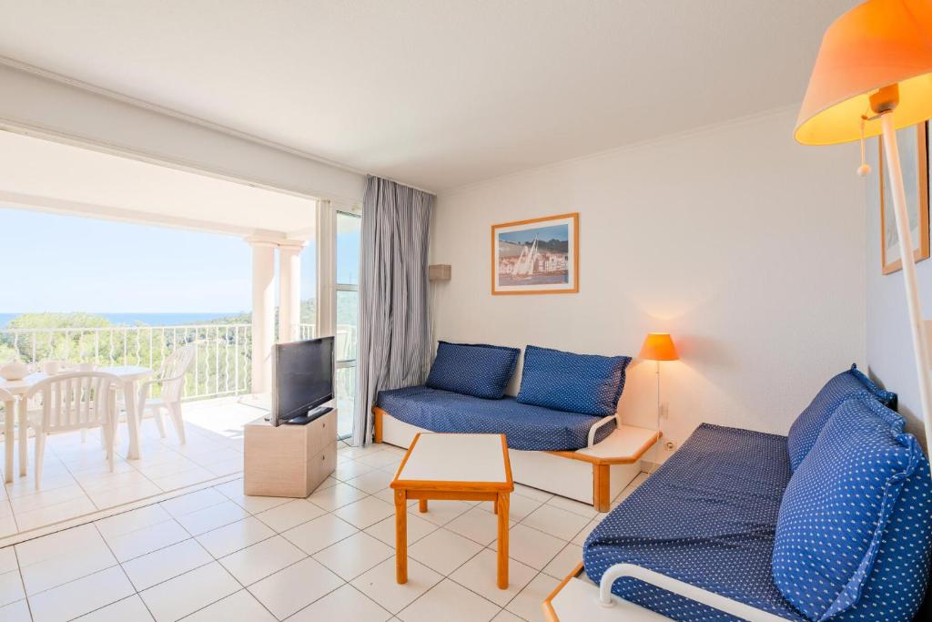 un salon avec un canapé bleu et une télévision dans l'établissement Résidence le Hameau de Cap Esterel - maeva Home - Appartement 2 pièces 7 personnes - Sélection MAE-7954, à Saint-Raphaël