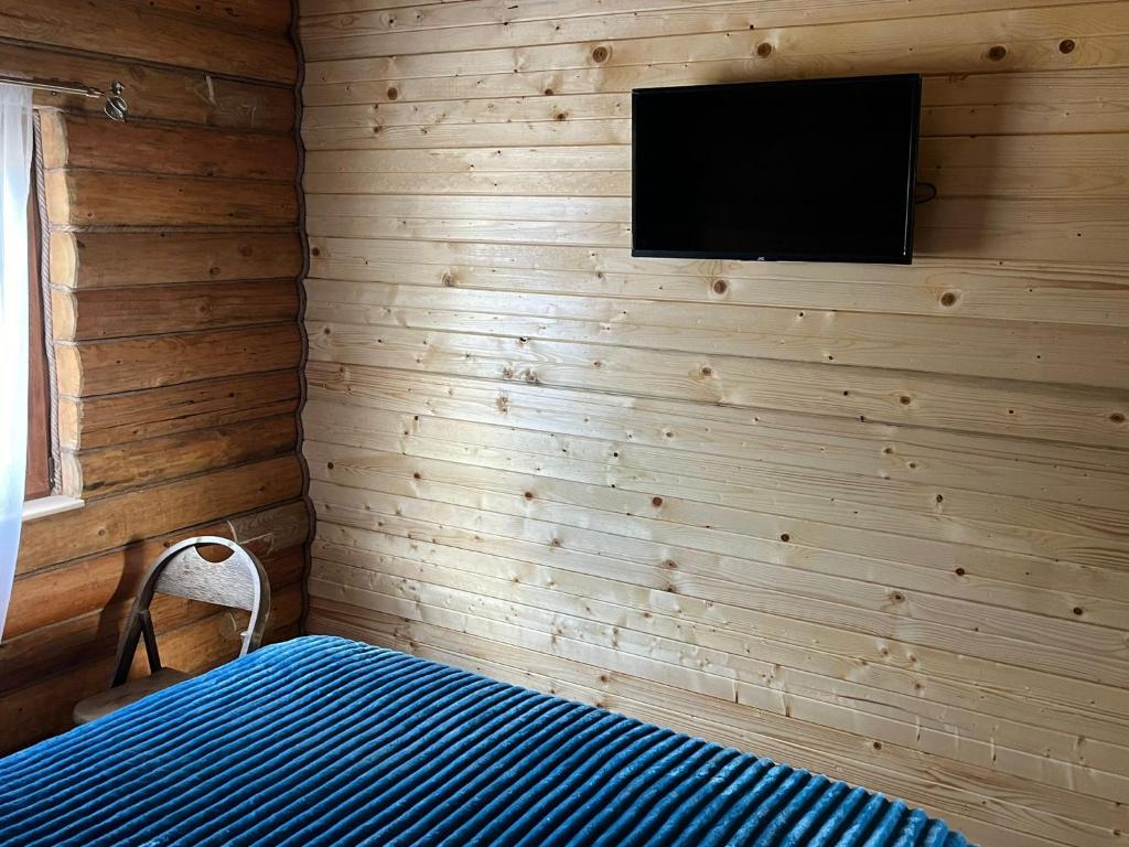 Habitación con cama y TV en la pared. en Cabana MOIGRAD-POROLISSUM en Zalău