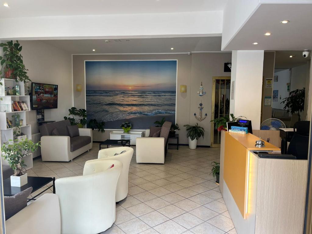 un vestíbulo con sillas blancas y una pintura del océano en Hotel Geppi en Pietra Ligure