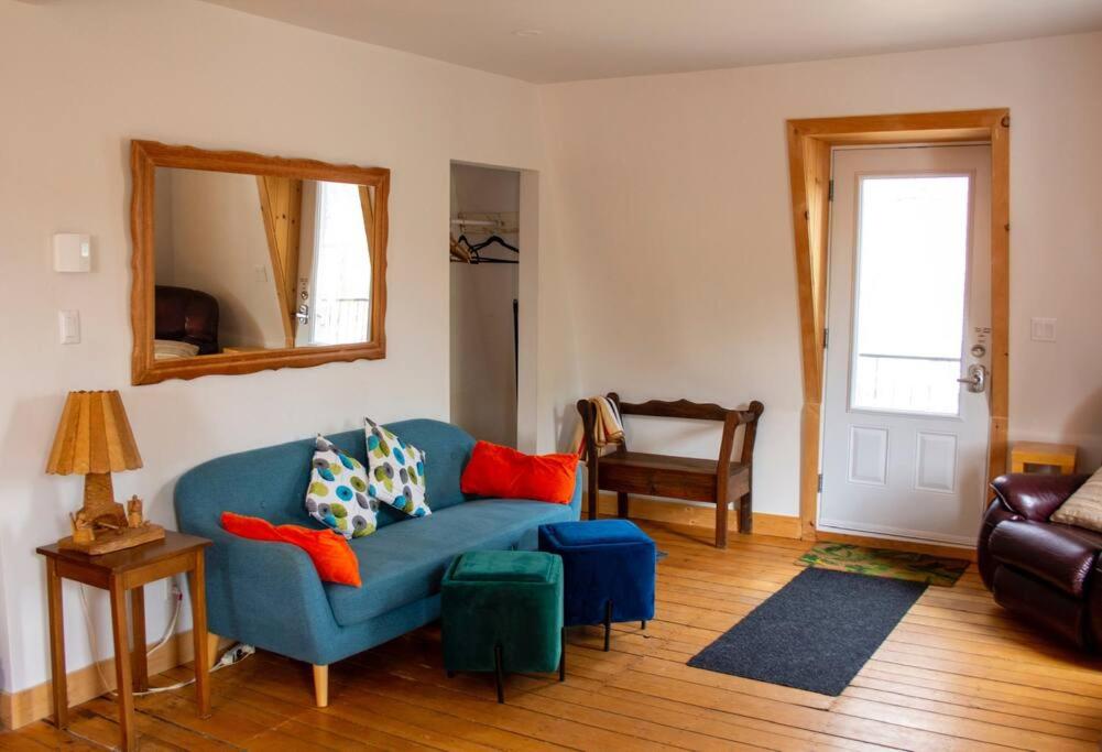 sala de estar con sofá azul y espejo en La Vérivraie/Truly -Hébergement touristique/Tourist accomodation en North Hatley