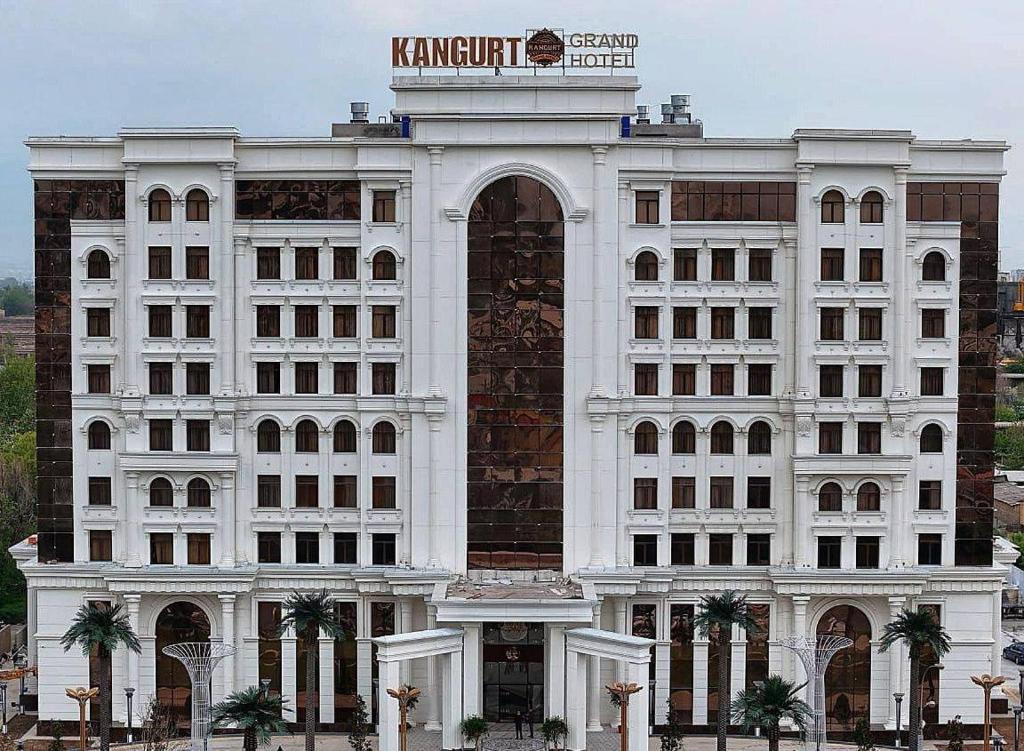 een groot wit gebouw met een bord erop bij KANGURT Grand Hotel in Doesjanbe