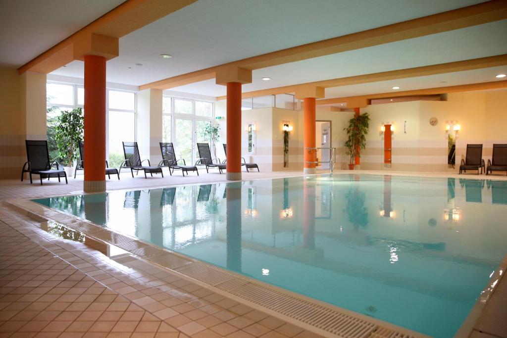 a large swimming pool in a hotel lobby with chairs at Sonnenhotel Hoher Hahn in Schwarzenberg