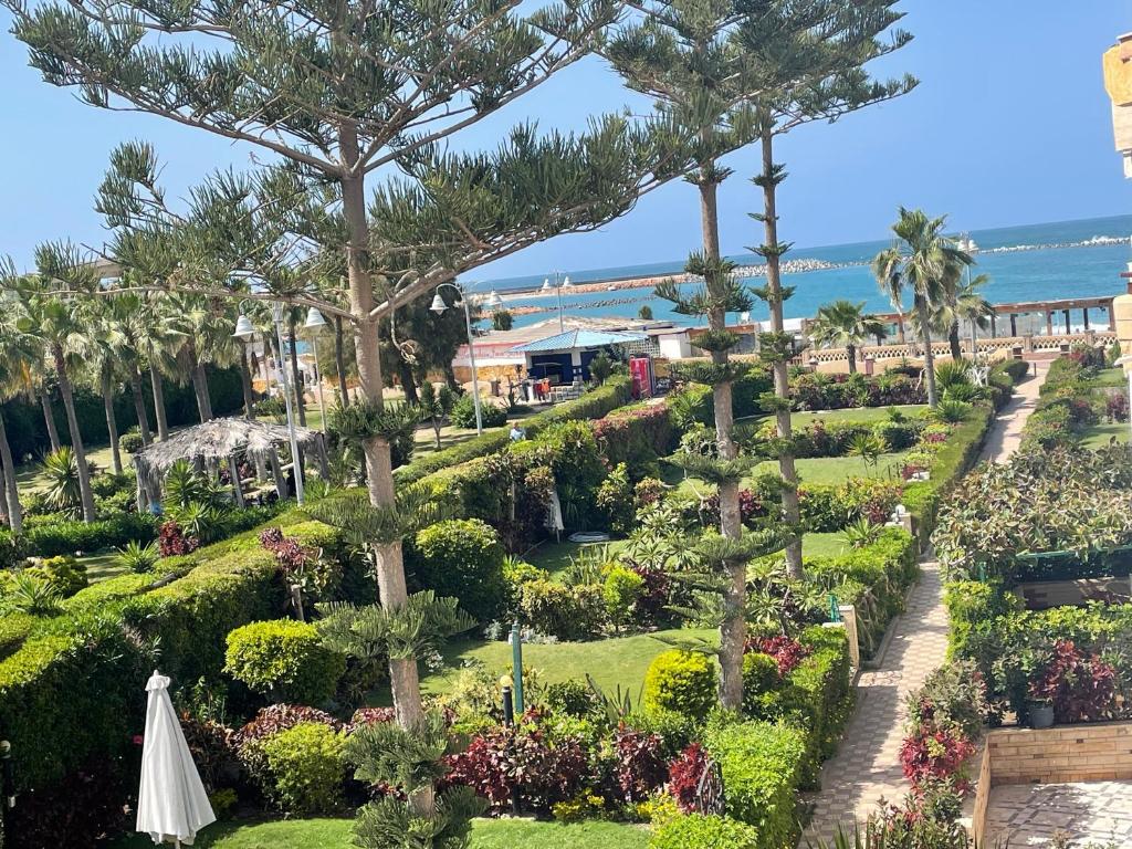 El-kobttan Chalet Sea Veiw - Maamourah في الإسكندرية: اطلالة على حديقة فيها نخل والمحيط