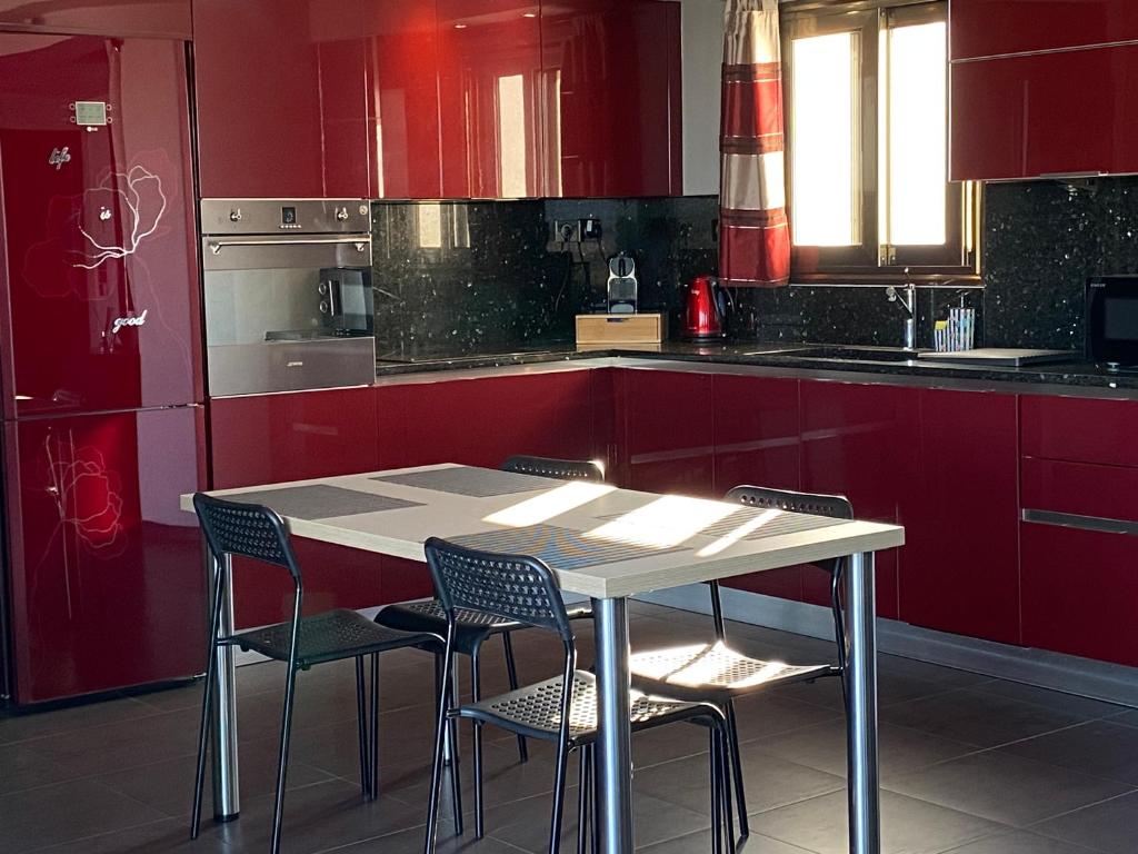 a kitchen with red cabinets and a table and chairs at Luxury view apartment 10min from Athens airport in Koropi