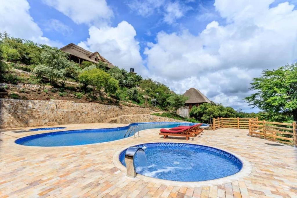 ein Pool mit einer Bank neben einem Haus in der Unterkunft Adere Safari lodge 