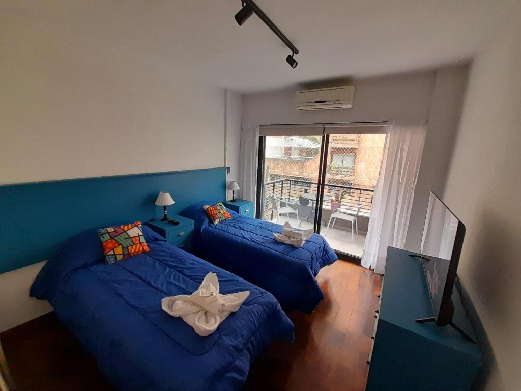 a bedroom with two beds with blue sheets and a window at Turismo Apart Palermo in Buenos Aires