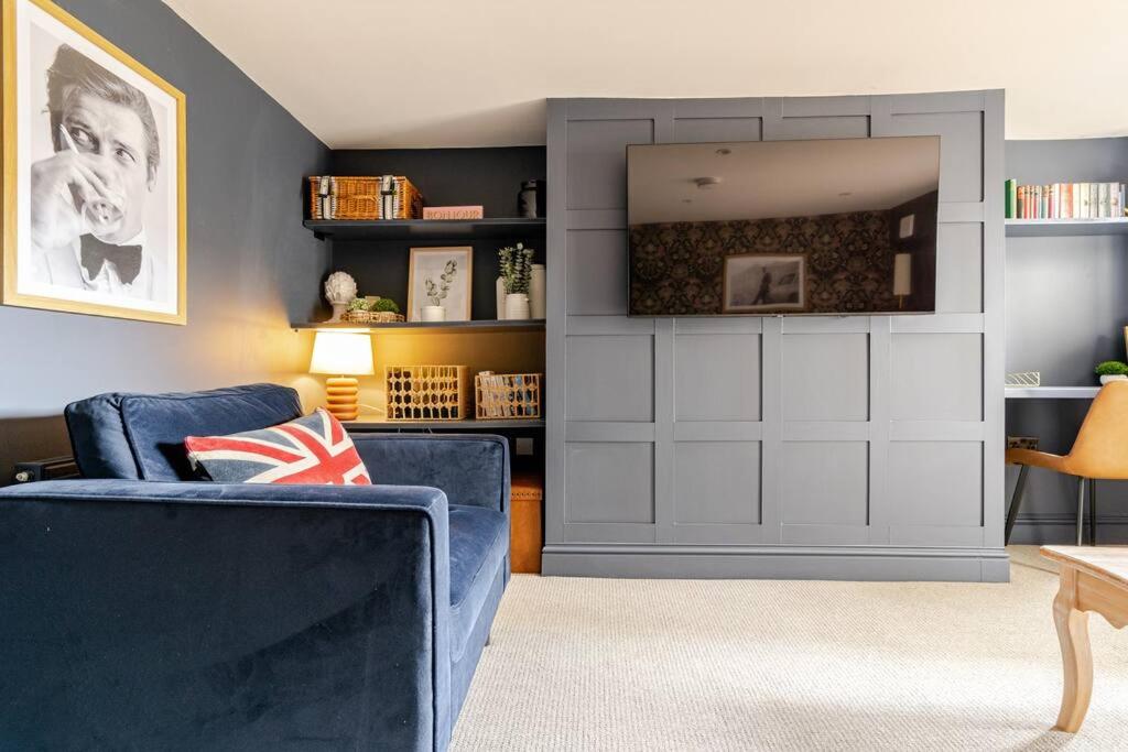 The Snug Den في Kent: غرفة معيشة مع أريكة زرقاء ومرآة