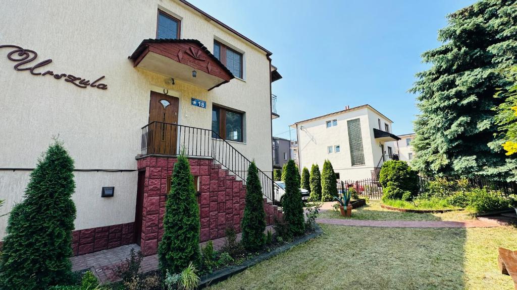 a white house with a brick wall at Willa Urszula in Krynica Morska