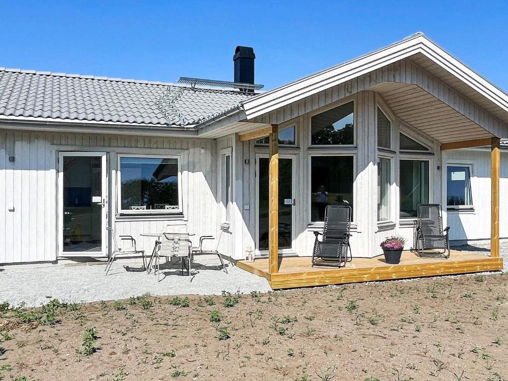 uma casa com um deque com cadeiras e uma mesa em Holiday home SÖLVESBORG X em Sölvesborg