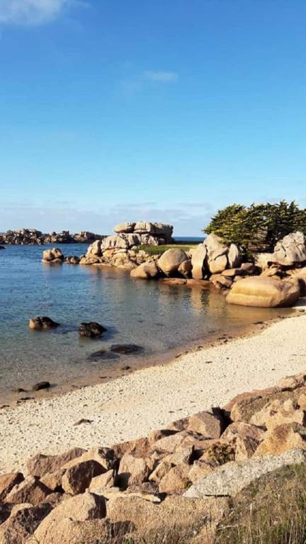 une plage avec un tas de rochers dans l'eau dans l'établissement Hébergement, Au couché du soleil, à Lannion