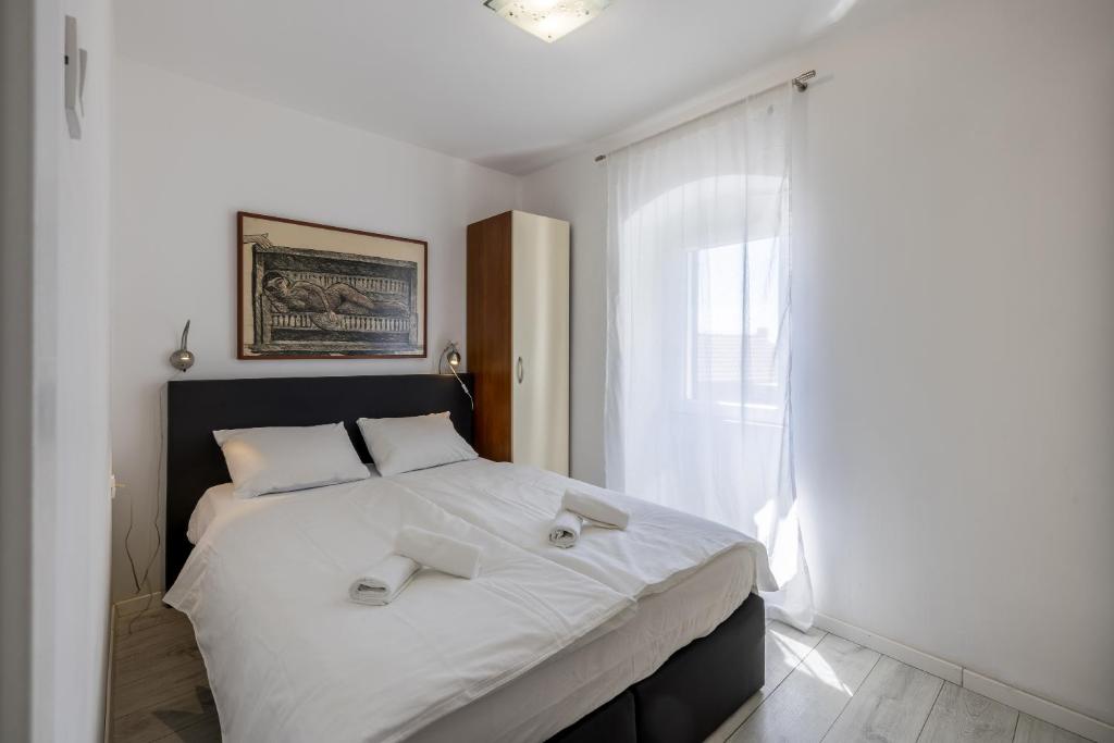 Un dormitorio con una gran cama blanca con ventana. en Split Central City Apartment, en Split