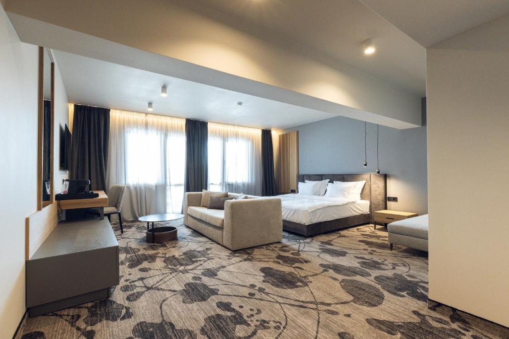パナギュリシテにあるKamengrad Hotel & SPAのベッドとソファ付きのホテルルーム