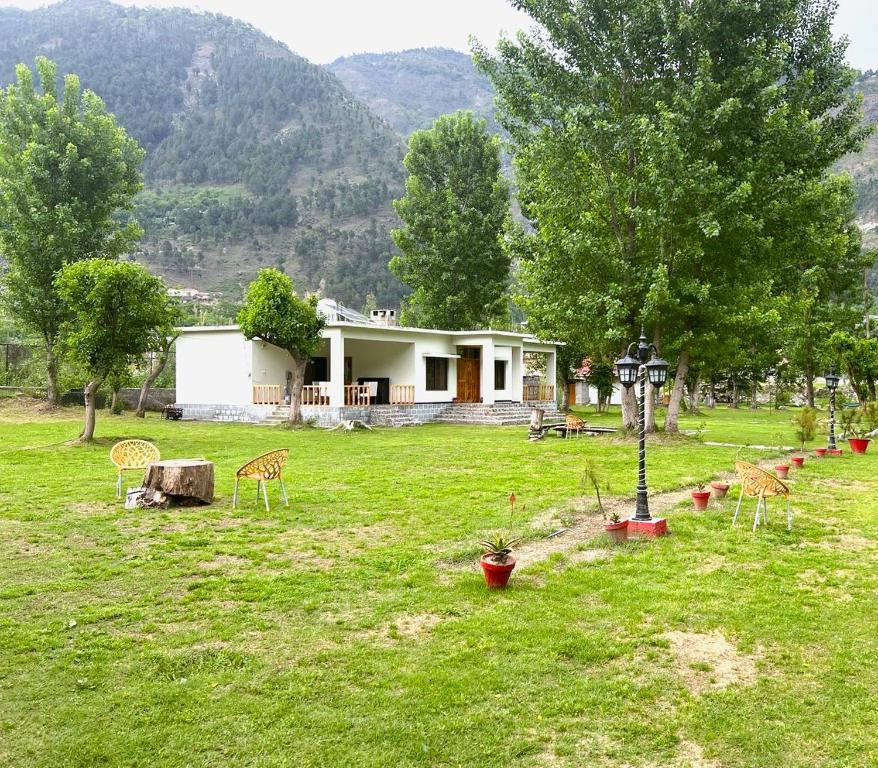 a house in a field with a yard with chairs at Two-Bedrooms Suite At Country Club Balakot in Bālākot