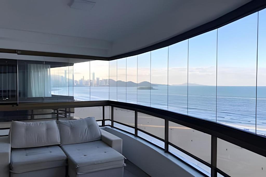 balcón con sofá y vistas al océano en Frente mar, espaço e conforto, en Balneário Camboriú