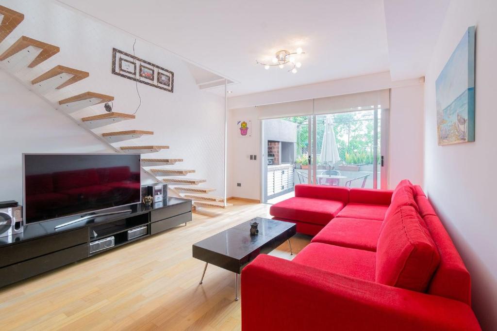 - un salon avec un canapé rouge et des escaliers dans l'établissement Tríplex Moderno con parrilla y jardín- Baires !, à Buenos Aires