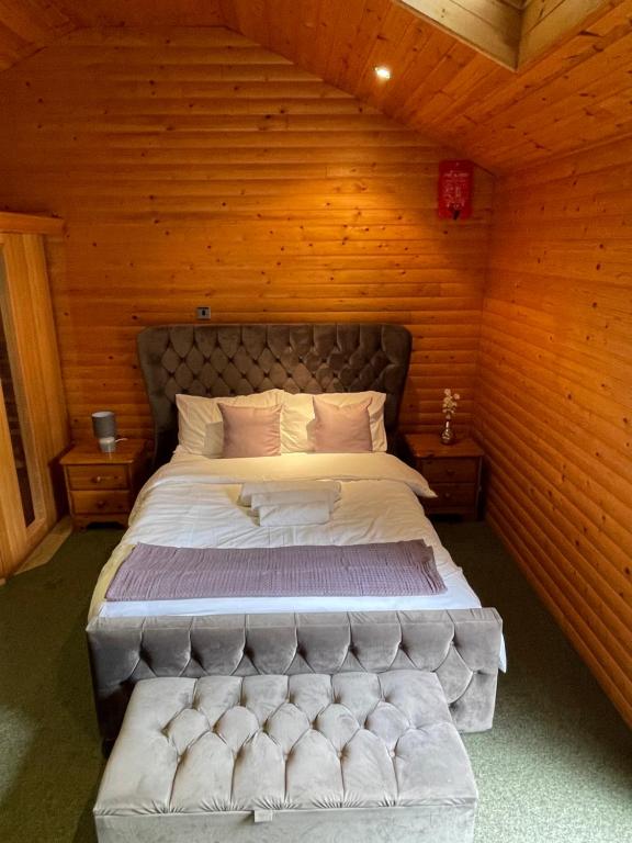 a bedroom with a large bed in a wooden wall at The Snug - Luxury En-suite Cabin with Sauna in Grays Thurrock in Grays Thurrock