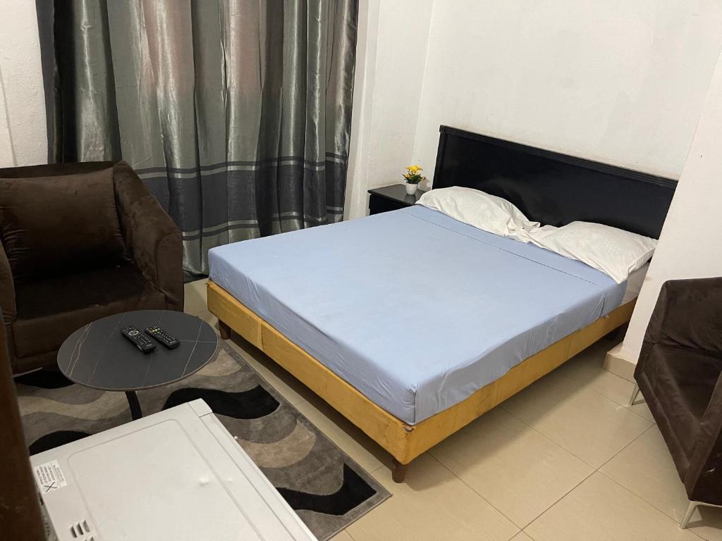 a bedroom with a bed and a chair and a table at Appartement Studio Damou in Bamako