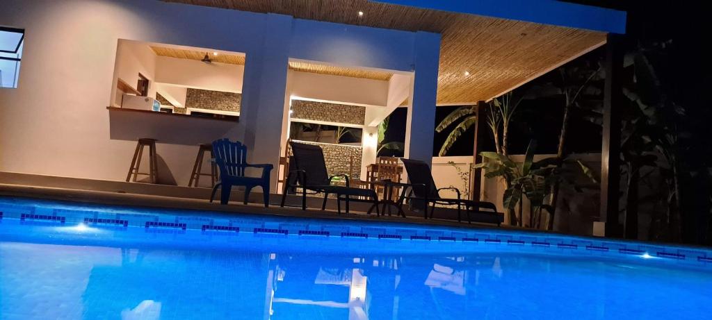 - une piscine avec des chaises et une maison dans l'établissement Casa Kapai, à Nosara