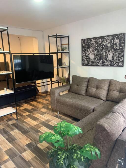 een woonkamer met een bank en een flatscreen-tv bij Lindo y acogedor apartamento in Medellín