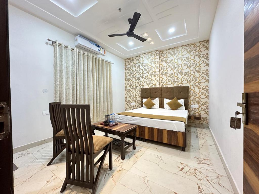Hotel EMBASSY 250 Meter From Golden Temple في أمريتسار: غرفة نوم بسرير وطاولة وكراسي