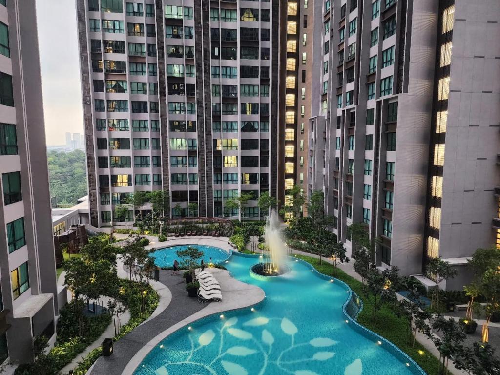 an aerial view of a pool with a fountain in front of tall buildings at Cubic Botanical Suites Bangsar South by HomeBrickz in Kuala Lumpur