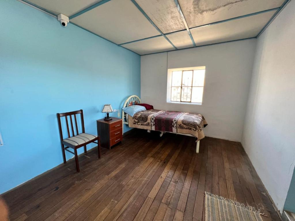 1 dormitorio con 1 cama, 1 silla y 1 ventana en Casa Rosita Sausa, en Jauja