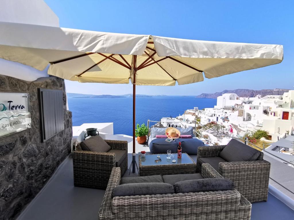 un tavolo e sedie sotto un ombrellone su un balcone di Aqua & Terra Traditional Cave Houses a Oia