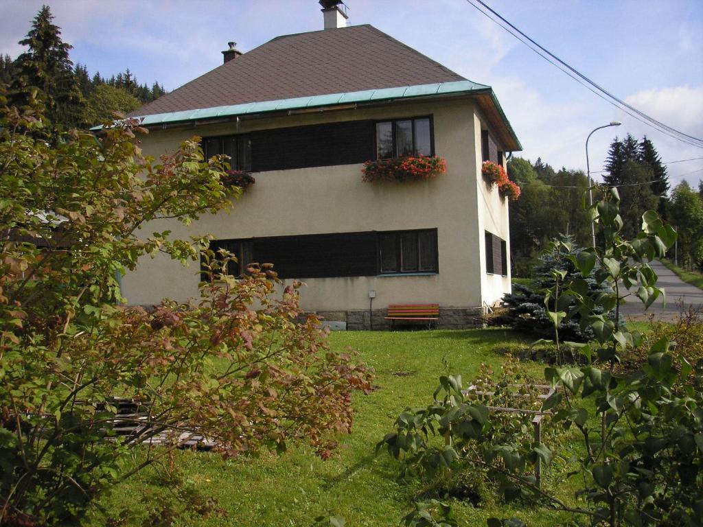 uma casa com um banco à frente em Apartment Arnika em Kořenov