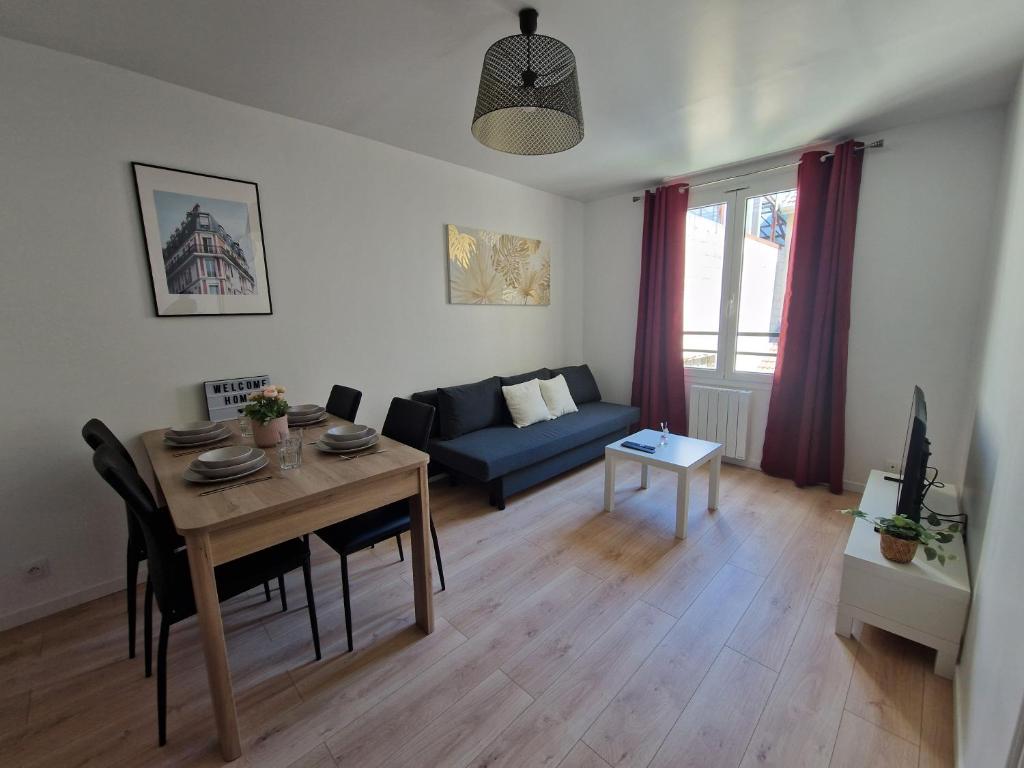 un salon avec une table et un canapé bleu dans l'établissement WD Saint Roch - Appartement 102 - Métro 7 Proche Paris, à Villejuif