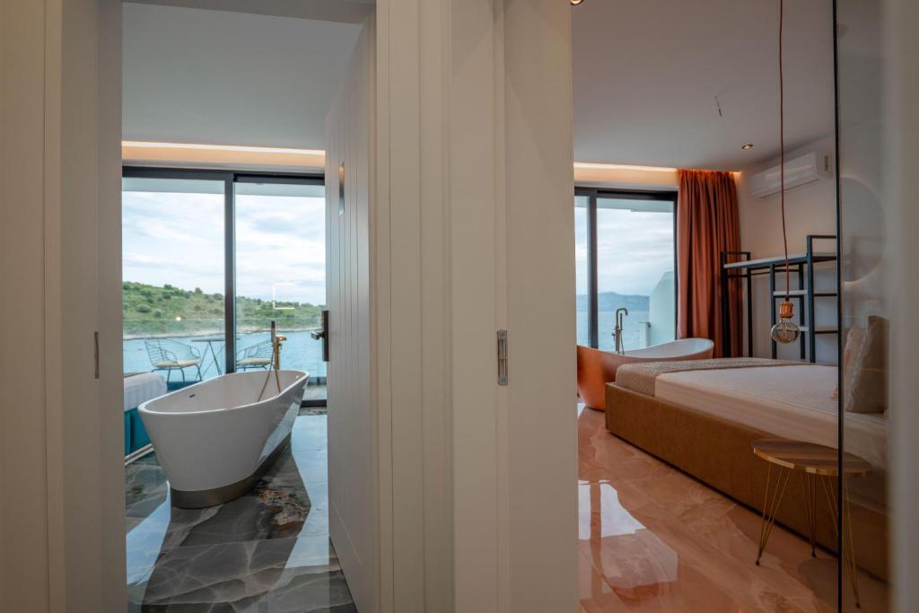 um quarto com uma banheira, uma cama, uma cama e uma janela em Siro Kerma Private Beach Villa em Sarandë