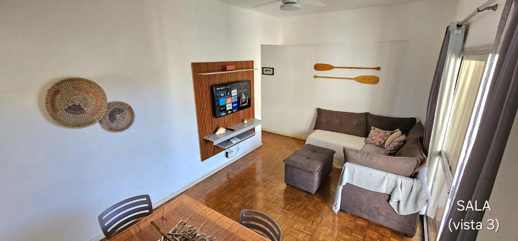 een woonkamer met een bank en een tv bij Centro Guarapari - espaço & conforto - WI-FI in Guarapari