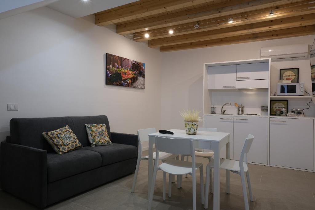 sala de estar con sofá, mesa y cocina en Baaria Apartments, en Bagheria