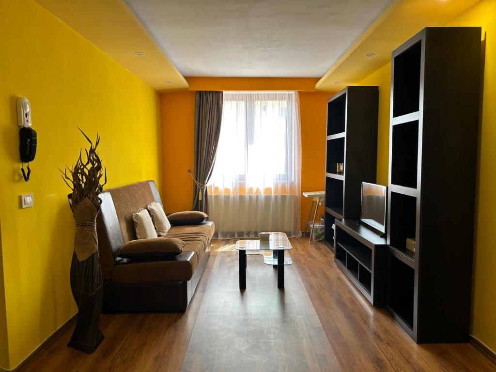 - un salon avec des murs jaunes, un canapé et une table dans l'établissement IANIS Apartment, à Orăştie