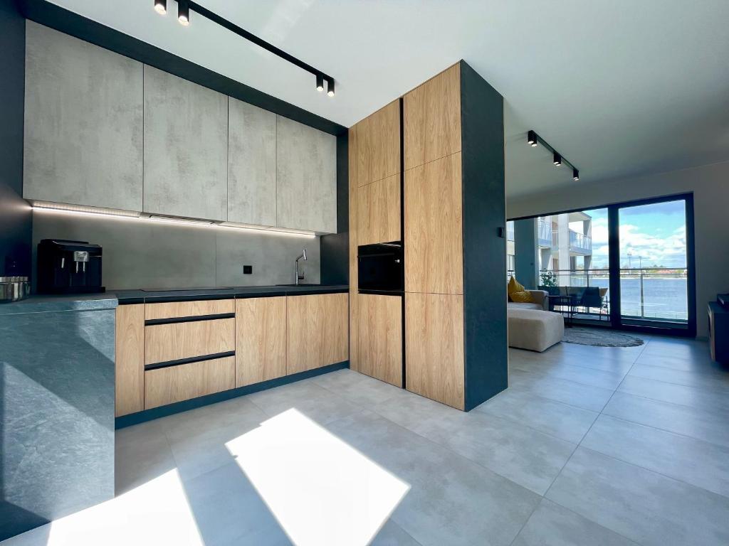 una cucina con armadi in legno e una grande finestra di Apartament HORYZONT z widokiem na Jezioro Drwęckie a Ostróda